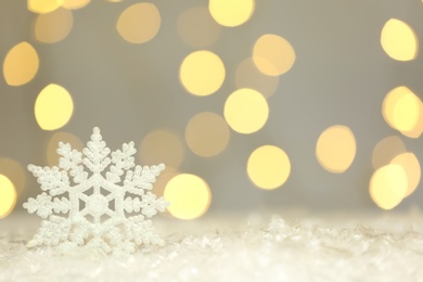 Photo of Beautiful decorative snowflake against blurred festive lights. Space for text