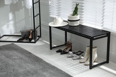 Photo of Bench with stylish women's shoes near window in dressing room. Interior design