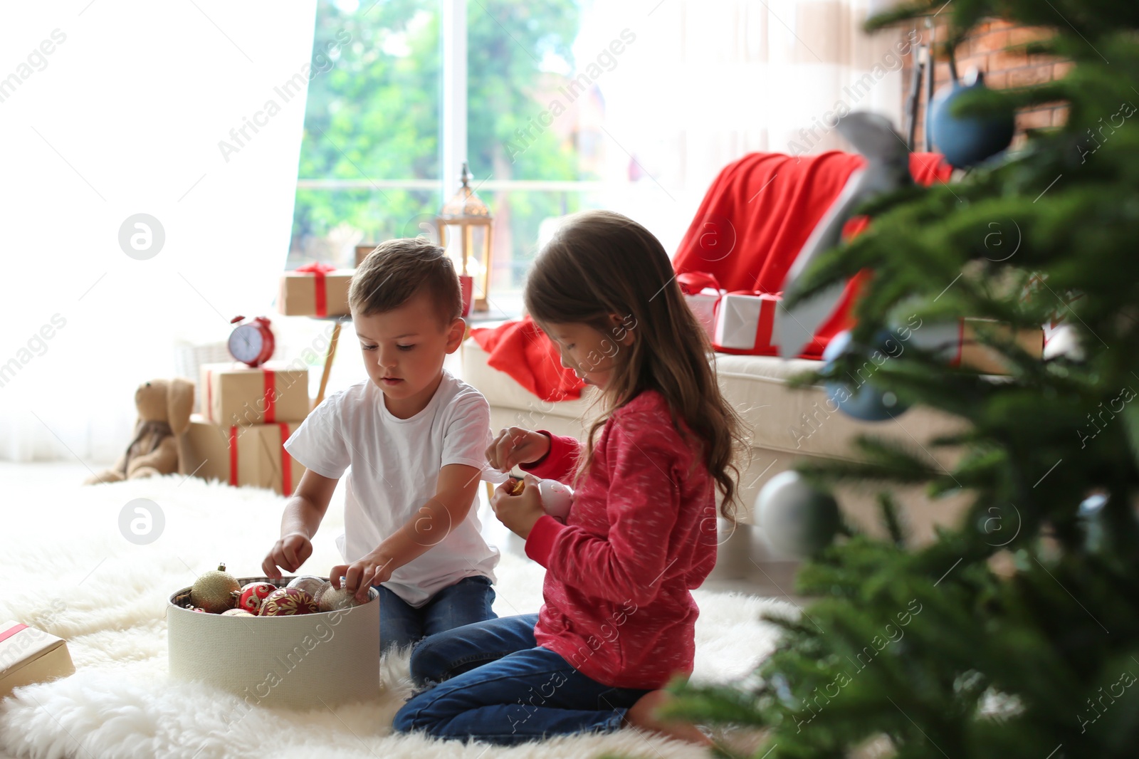 Photo of Children decorating Christmas tree together at home