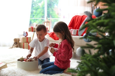 Children decorating Christmas tree together at home
