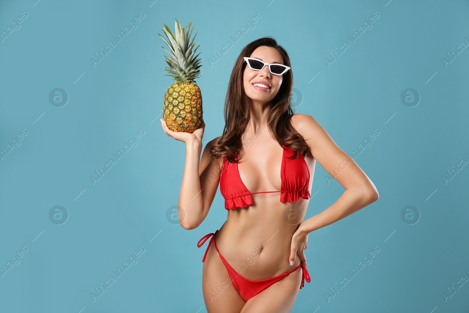 Photo of Beautiful woman in stylish bikini with pineapple on blue background