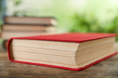 Closed hardcover book on wooden table against blurred background