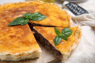 Photo of Delicious pie with minced meat on wooden tray, closeup