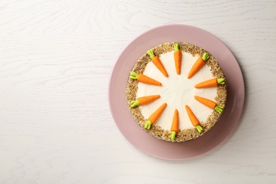 Dish with tasty carrot cake on white wooden table, top view. Space for text