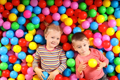 Photo of Cute children playing in ball pit indoors, top view