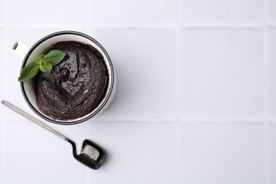 Photo of Tasty chocolate mug pie and spoon on white table, top view with space for text. Microwave cake recipe