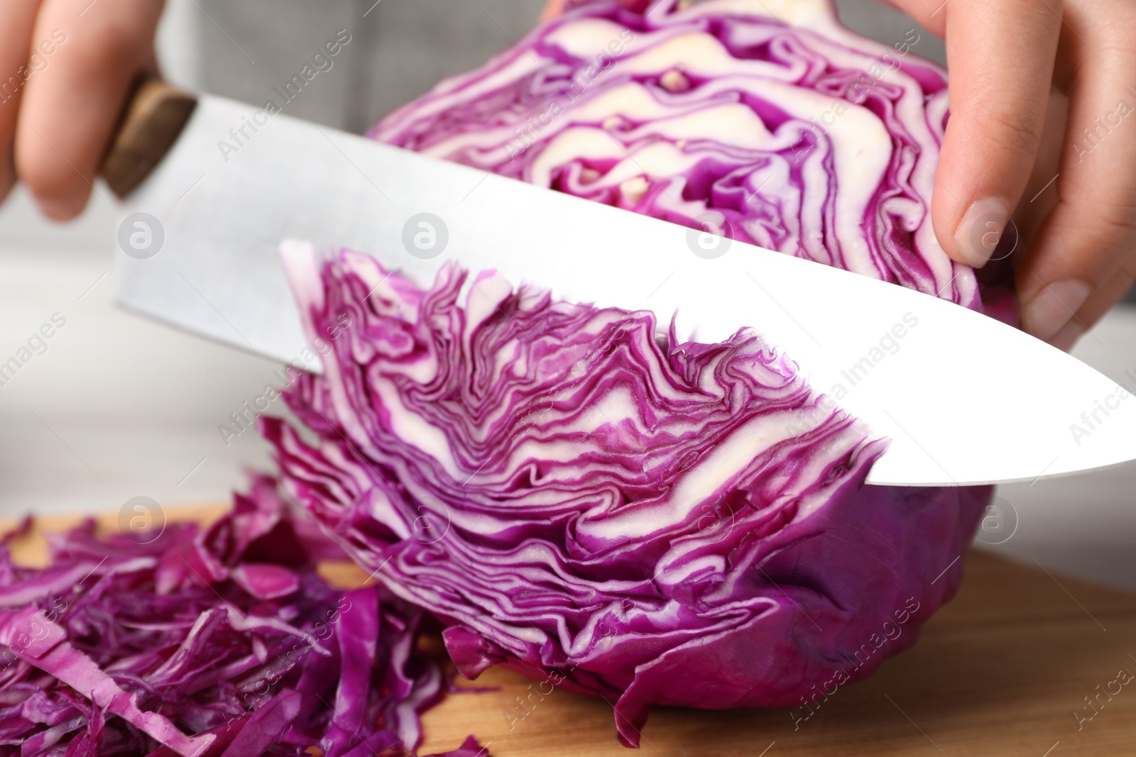 Photo of Woman cutting fresh red cabbage at table, closeup