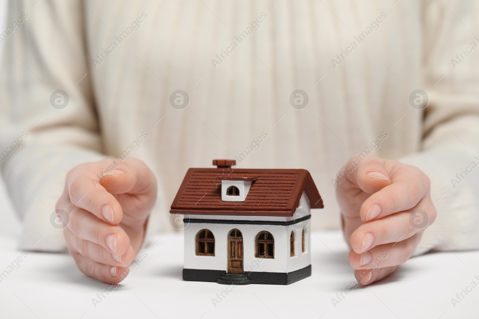 Photo of Home security concept. Woman with house model at white table, closeup