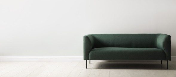 Photo of Comfortable green sofa near white wall indoors, space for text. Interior design