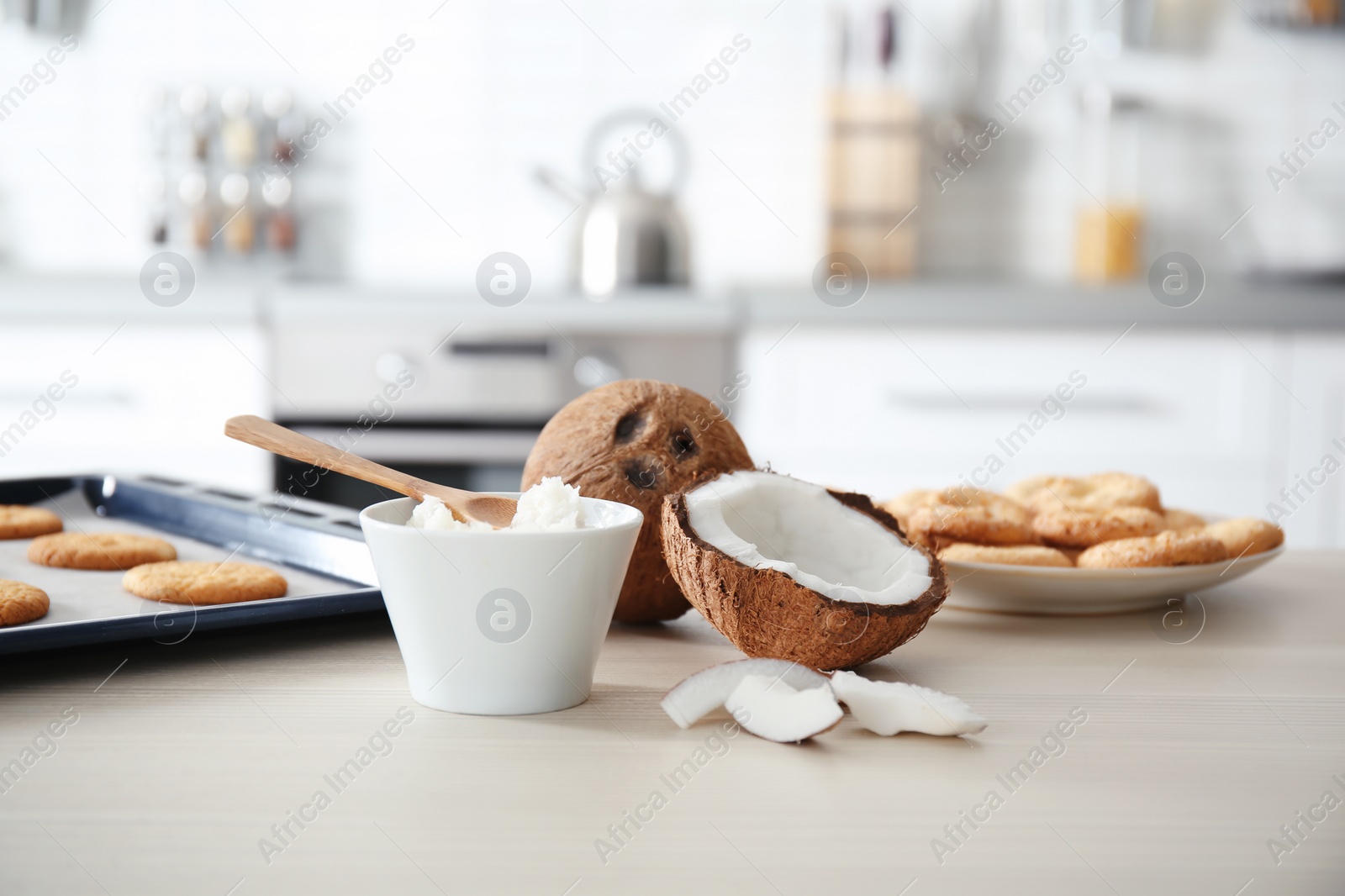 Photo of Bowl with coconut oil and nut pieces on wooden table