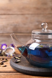 Photo of Organic blue Anchan in glass pot on wooden table, space for text. Herbal tea