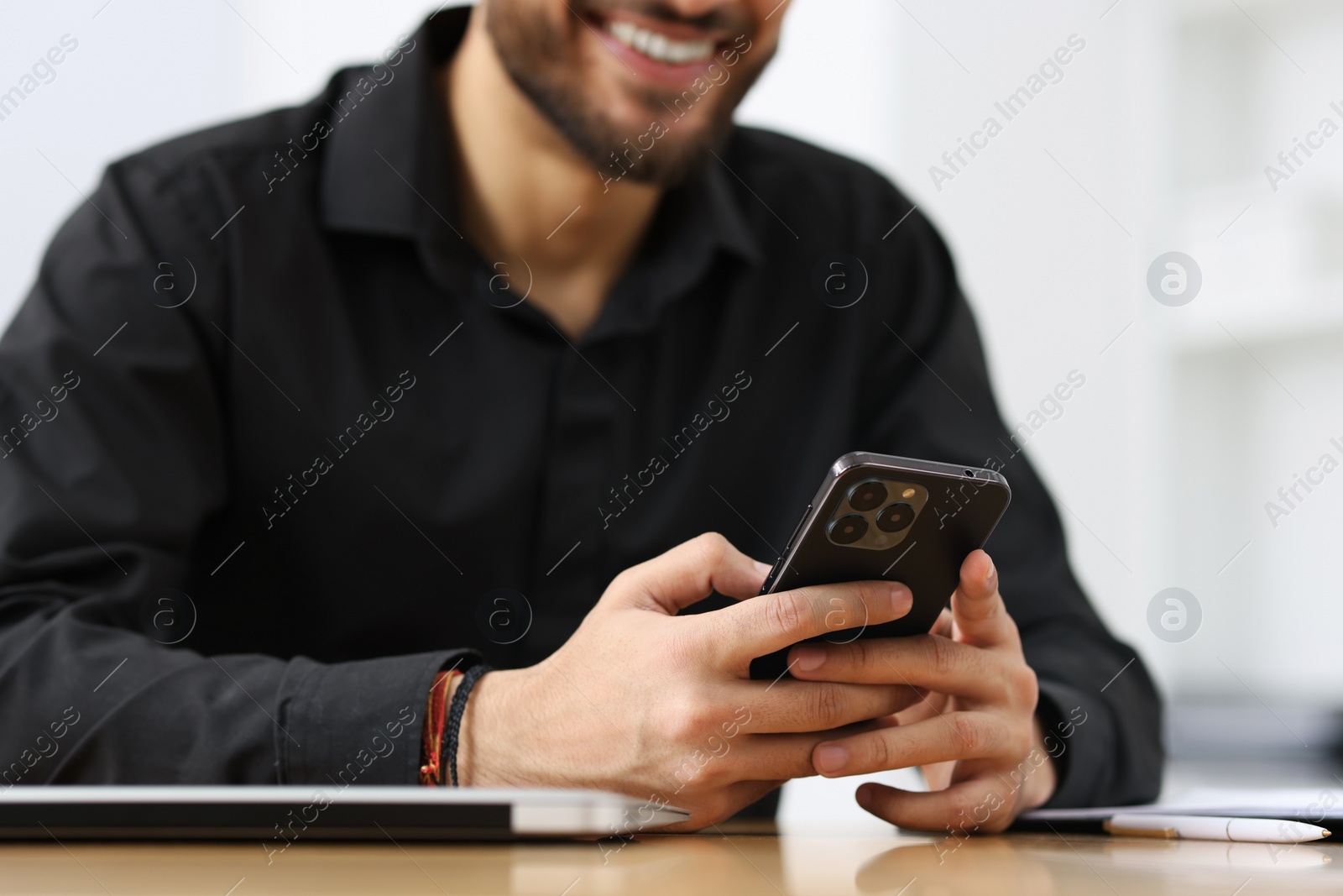 Photo of Man using smartphone at table in office, closeup