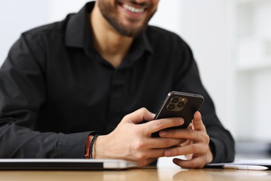 Photo of Man using smartphone at table in office, closeup