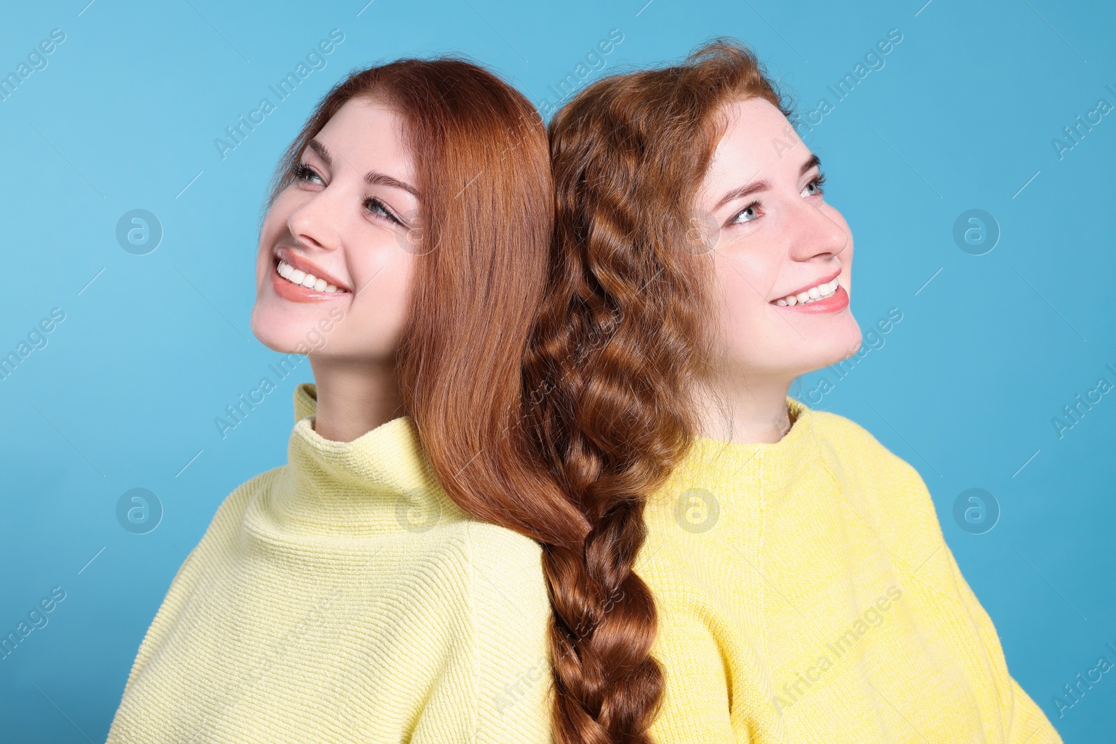 Photo of Portrait of beautiful young redhead sisters on light blue background