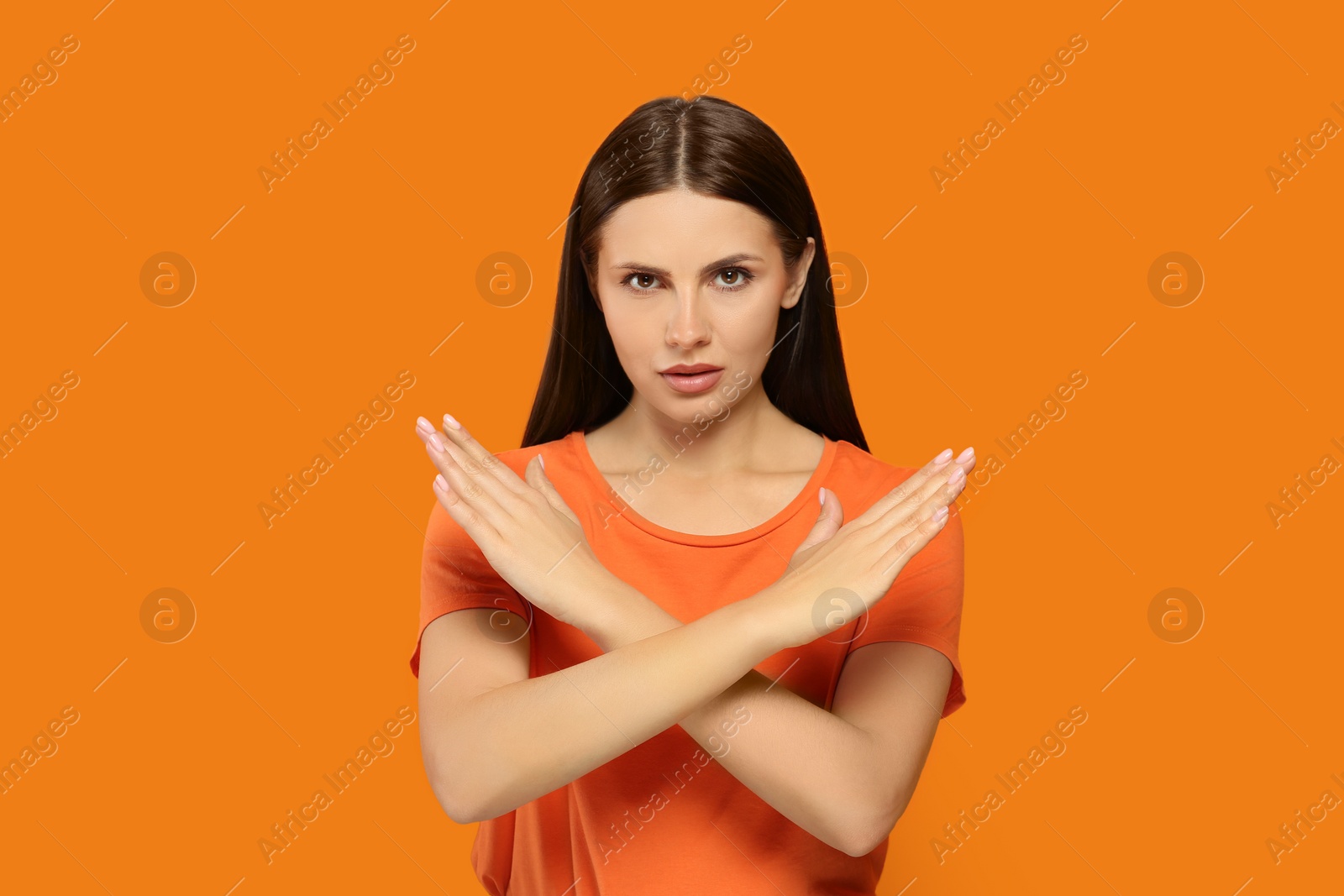 Photo of Woman with crossed hands on orange background. Stop gesture