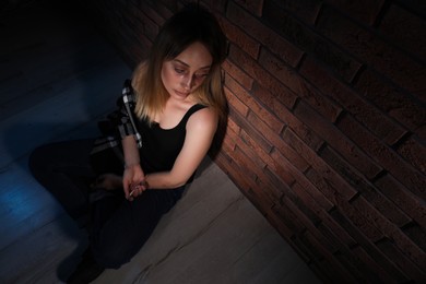 Photo of Overdosed drug addicted woman near brick wall. Space for text