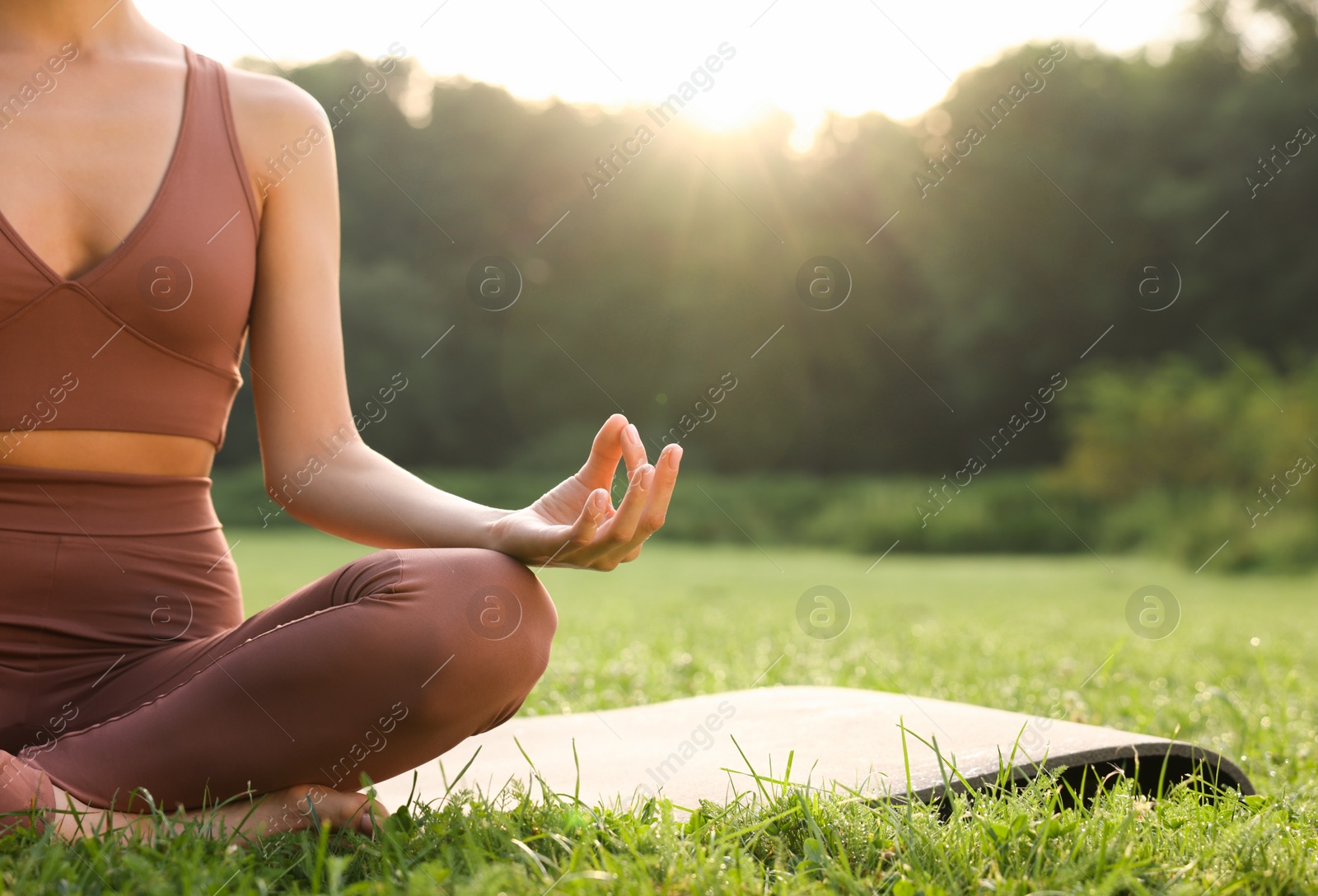 Photo of Woman practicing Padmasana on yoga mat outdoors, closeup and space for text. Lotus pose