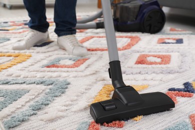 Photo of Man cleaning carpet with vacuum cleaner at home, closeup. Space for text