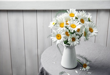 Photo of Vase with beautiful chamomile flowers on table