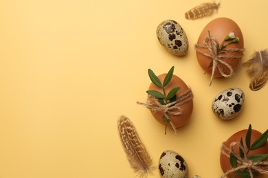 Happy Easter. Chicken and quail eggs with natural decor on yellow background, flat lay. Space for text