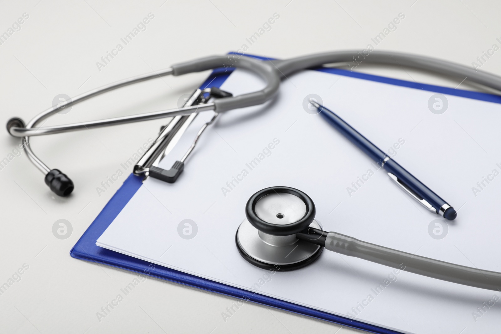 Photo of Stethoscope and clipboard on beige background, closeup