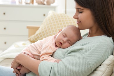 Mother holding her sleeping baby at home