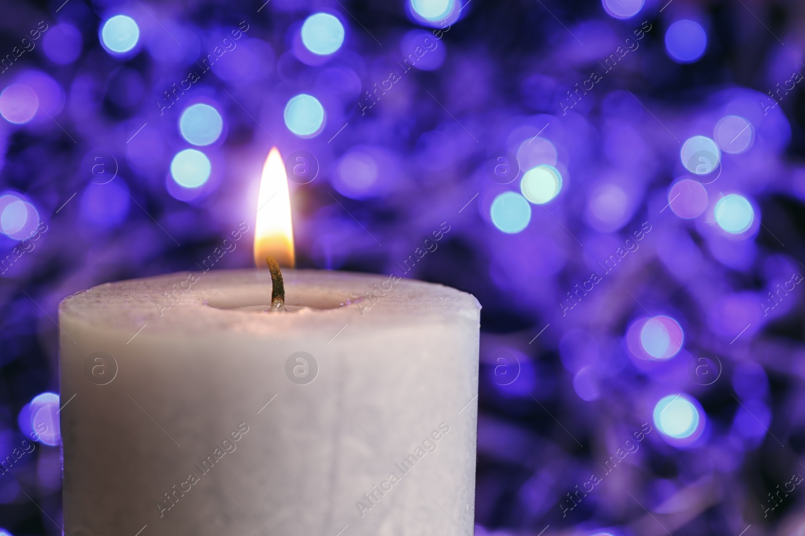 Photo of Burning wax candle on blurred background, closeup