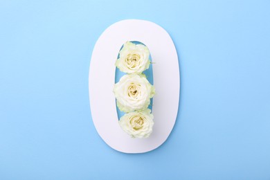 Paper number 0 and beautiful flowers on light blue background, top view