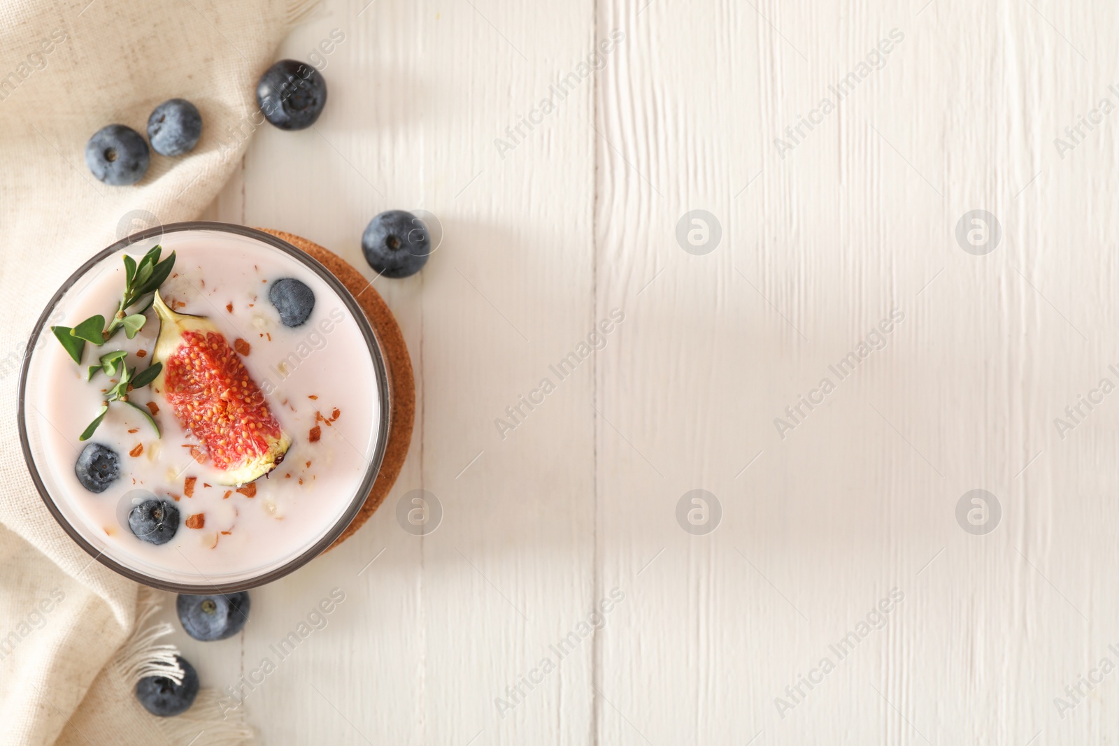 Photo of Delicious fig smoothie in glass on white wooden table, flat lay. Space for text