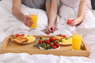 Photo of Couple eating tasty breakfast in bed, closeup