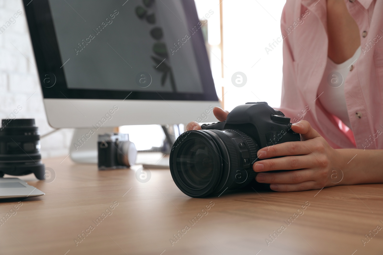 Photo of Professional photographer with camera working at table in office, closeup