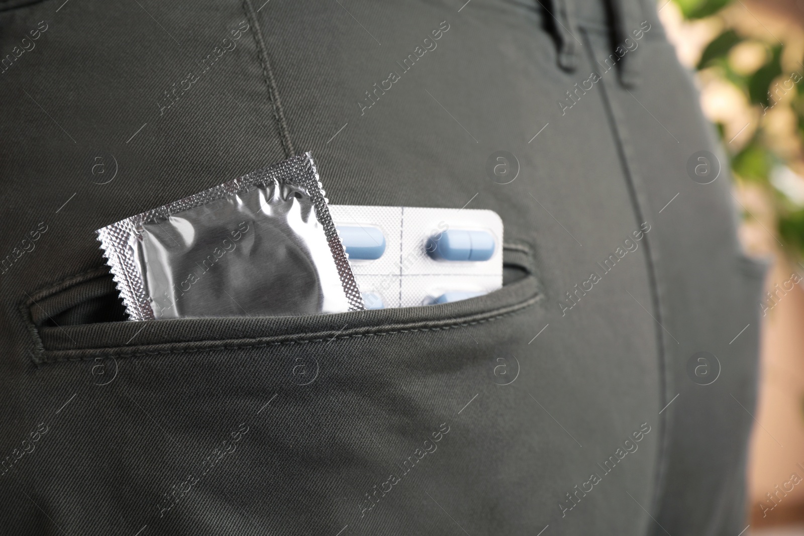 Photo of Jeans with pills and condom in pocket, closeup. Potency problem