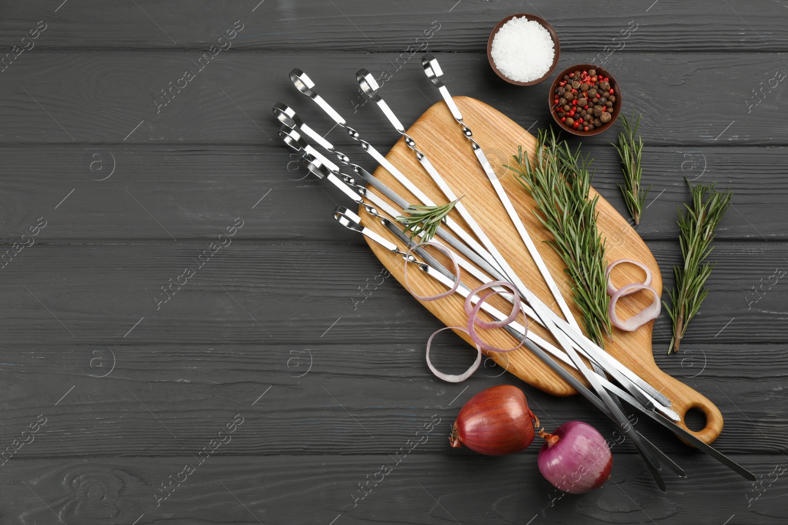 Photo of Flat lay composition with metal skewers on black wooden table. Space for text