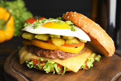 Tasty burger with fried egg on wooden board