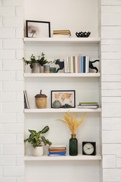Photo of Cat shaped bookends with books and different decor on shelves indoors. Interior design
