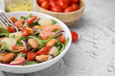 Photo of Delicious pomelo salad with tomatoes and mussels on white textured table, closeup. Space for text
