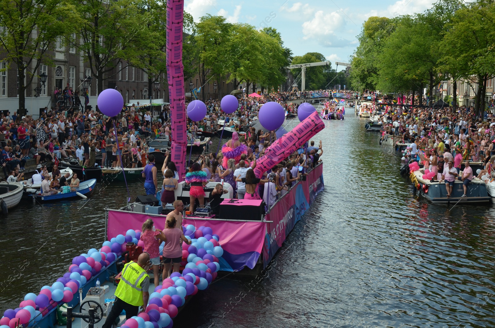 Photo of AMSTERDAM, NETHERLANDS - AUGUST 06, 2022: Many people in boats at LGBT pride parade on river