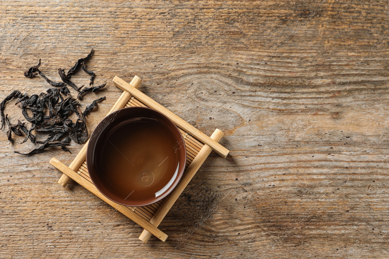 Photo of Cup of Da Hong Pao oolong and tea leaves on table, top view with space for text