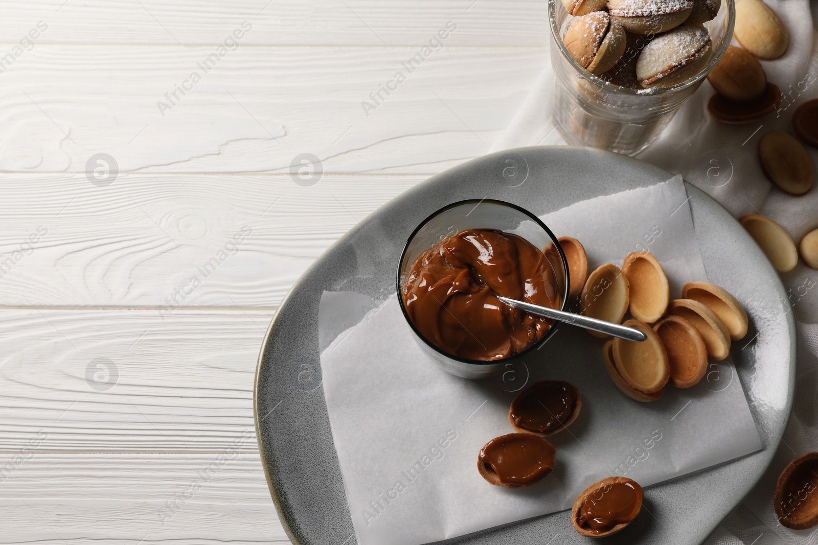 Photo of Delicious walnut shaped cookies with condensed milk on white wooden table, flat lay. Space for text