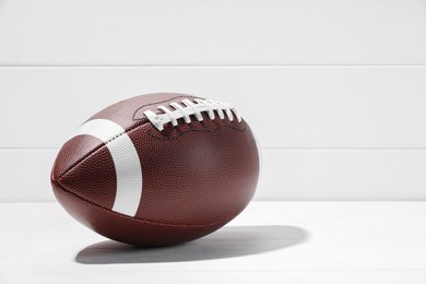 American football ball on white wooden background, space for text