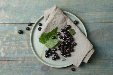 Photo of Ripe blackcurrants and leaves on wooden rustic table, flat lay