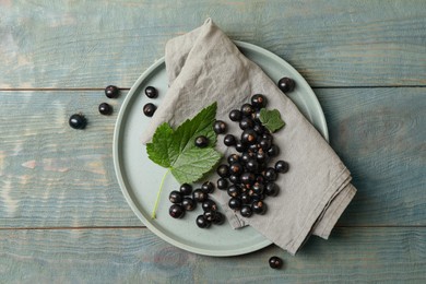 Ripe blackcurrants and leaves on wooden rustic table, flat lay