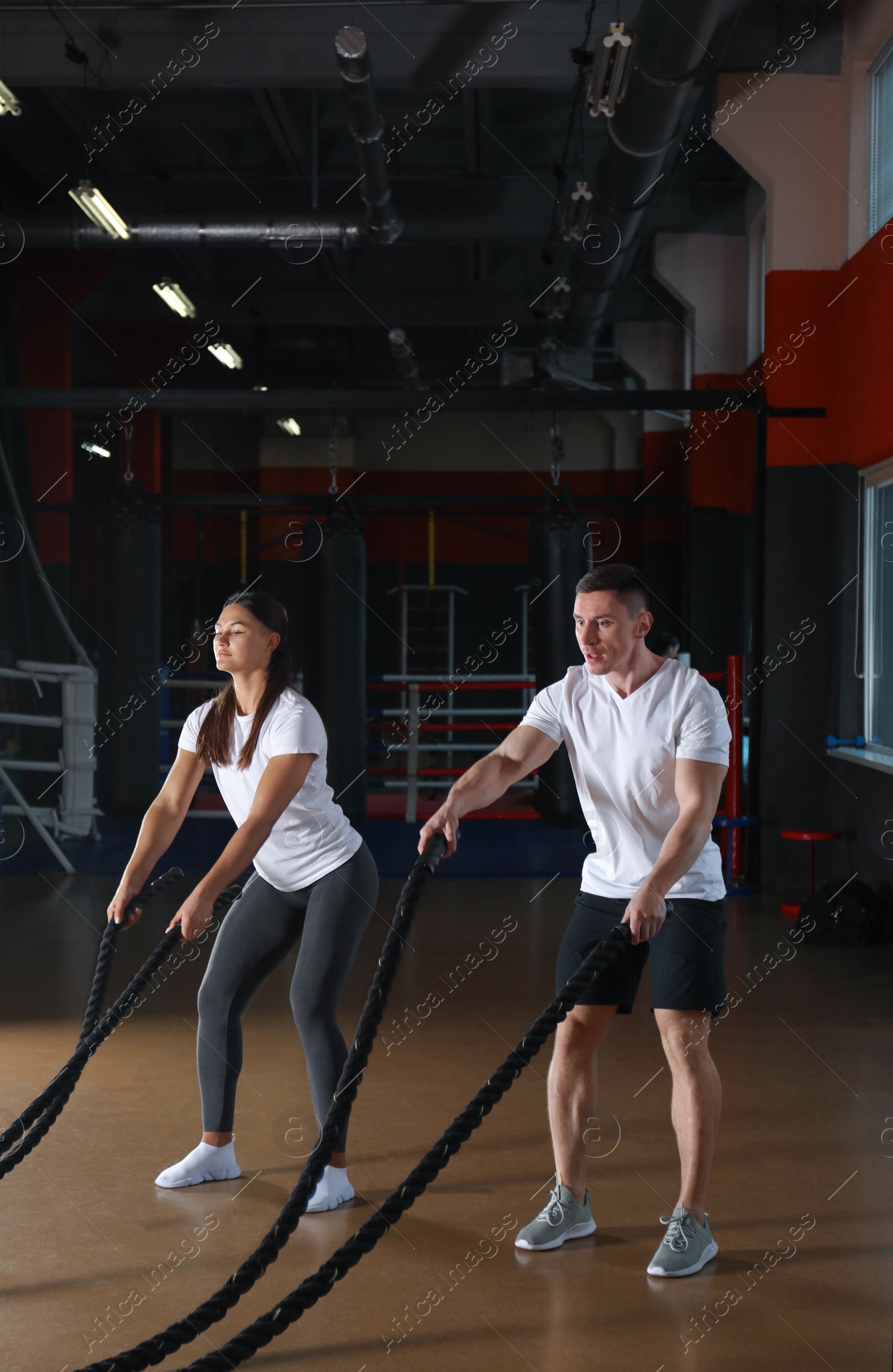 Photo of Couple working out with battle ropes in gym