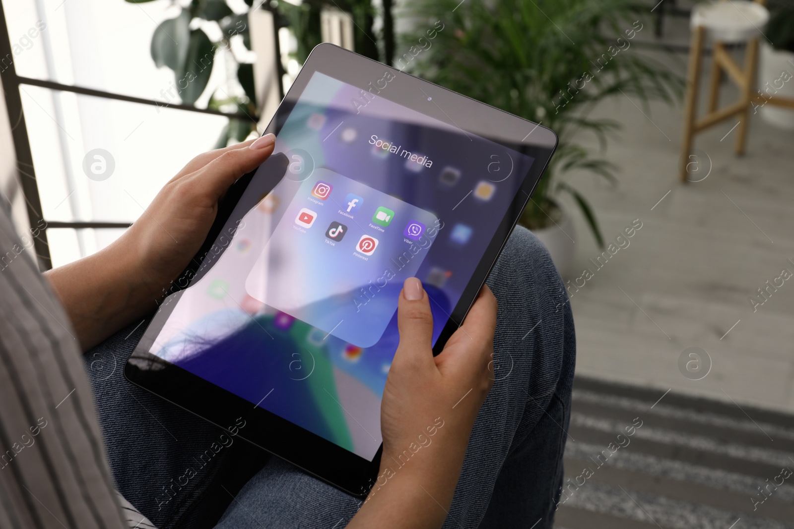 Photo of MYKOLAIV, UKRAINE - AUGUST 11, 2021: Woman using tablet indoors, closeup. Screen with different social media icons