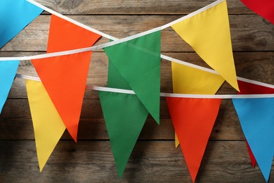 Photo of Colorful bunting party flags hanging on wooden wall. Festive decor
