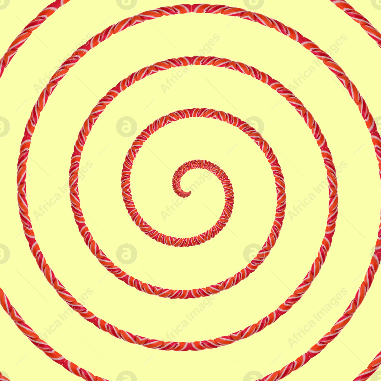 Image of Spiral of twisted candy stick on pale light yellow background