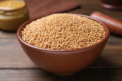 Mustard seeds in bowl on wooden table, closeup