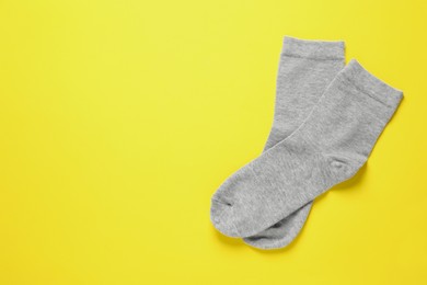 Photo of Pair of grey socks on yellow background, flat lay. Space for text