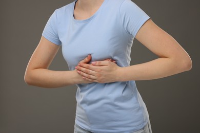 Photo of Woman having heart attack on grey background, closeup