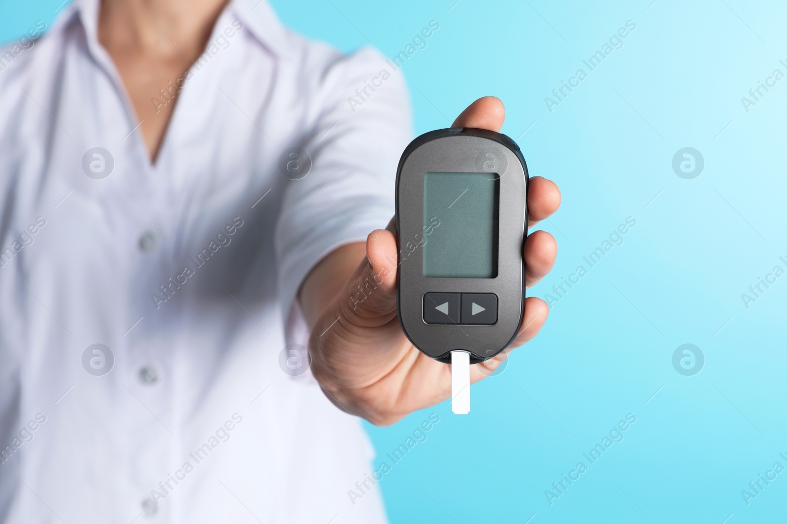 Photo of Female doctor holding digital glucometer on color background, closeup. Medical object